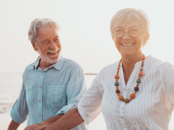 Couple of old mature people walking on the sand together and hav