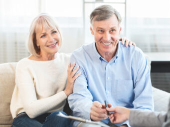 Happy mature couple talking to financial advisor at home
